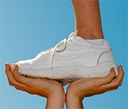 A person standing one-footed on the hands of another person. - Copyright – Stock Photo / Register Mark
